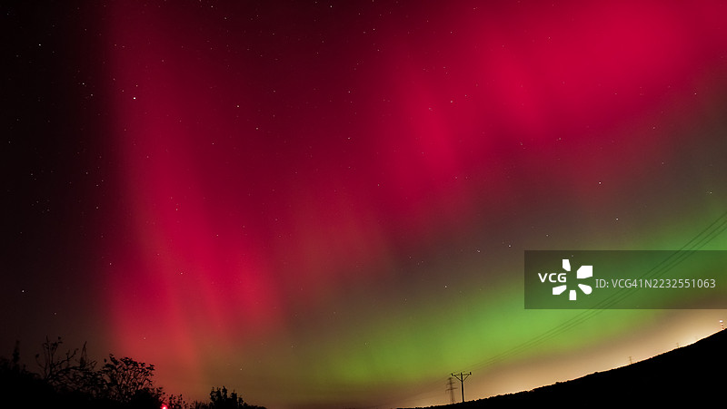 夜晚树木剪影下壮观的北极光展示图片素材