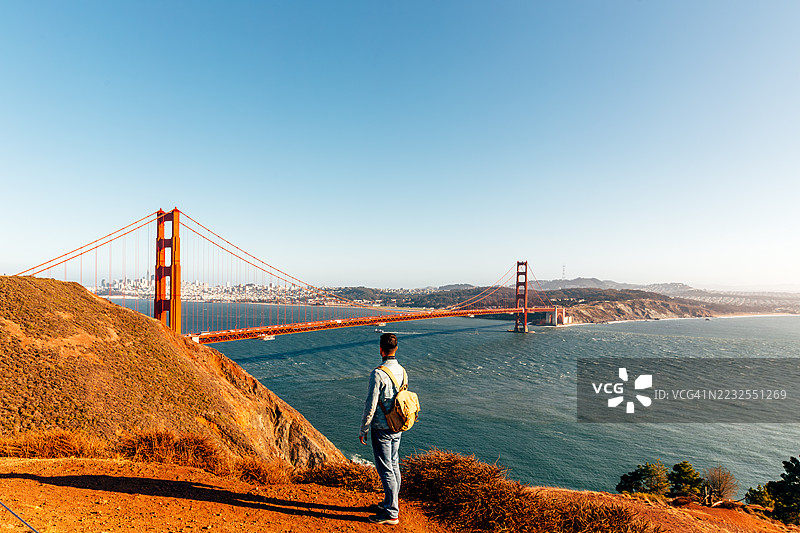 背着背包的男子在阳光明媚的日子里，从悬崖上俯瞰旧金山的金门大桥，加利福尼亚州，美国图片素材