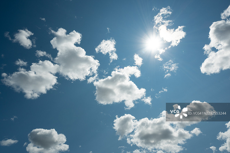 阳光透过蓝天中的蓬松云朵洒下图片素材