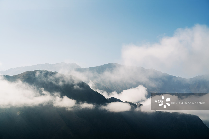 厚厚云海中的山谷航拍图，险峻的绿色和灰色山峰从中升起。图片素材