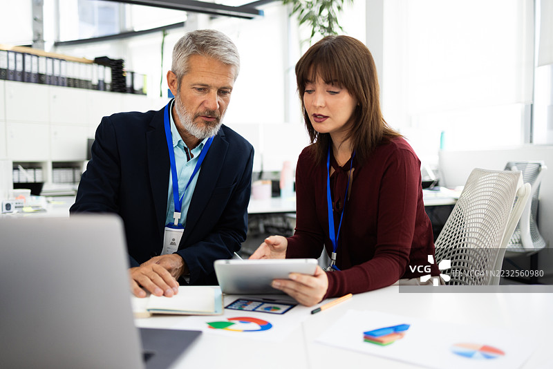 商务人士在办公室使用平板电脑和笔记本电脑共同工作图片素材