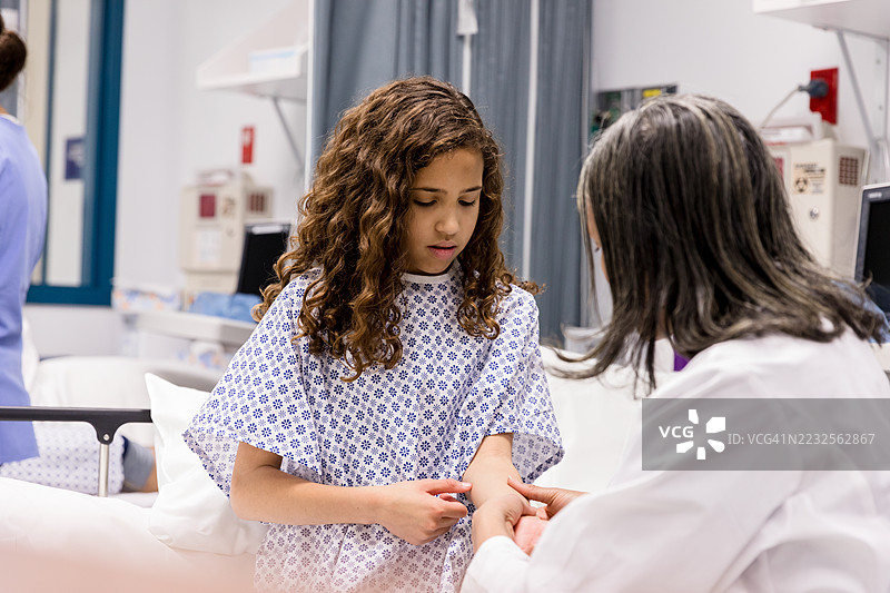 医生在医院病房检查年轻患者的手臂图片素材