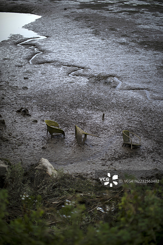 自然中泥土里被遗弃的椅子和家具，垃圾污染水源和自然环境图片素材