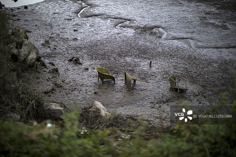 自然中泥土里被遗弃的椅子和家具，垃圾污染水源和自然环境图片素材