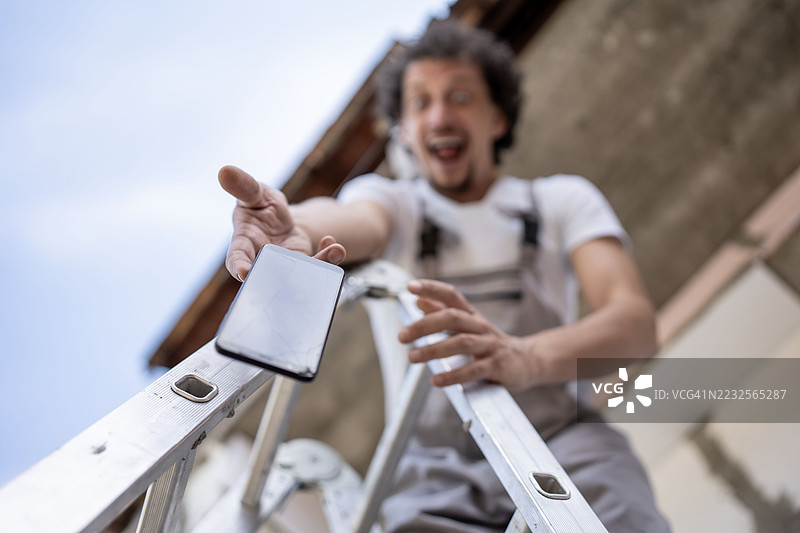 男子在动态瞬间爬梯时掉落智能手机图片素材