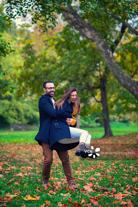 美丽的年轻情侣在秋天的森林中享受乐趣图片素材