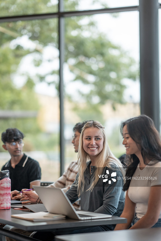 多元化的学生群体在明亮的教室环境中合作使用笔记本电脑图片素材