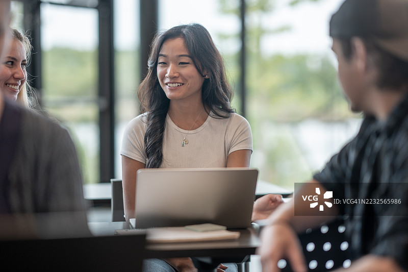 年轻亚洲女性在友好的小组中使用笔记本电脑进行合作图片素材