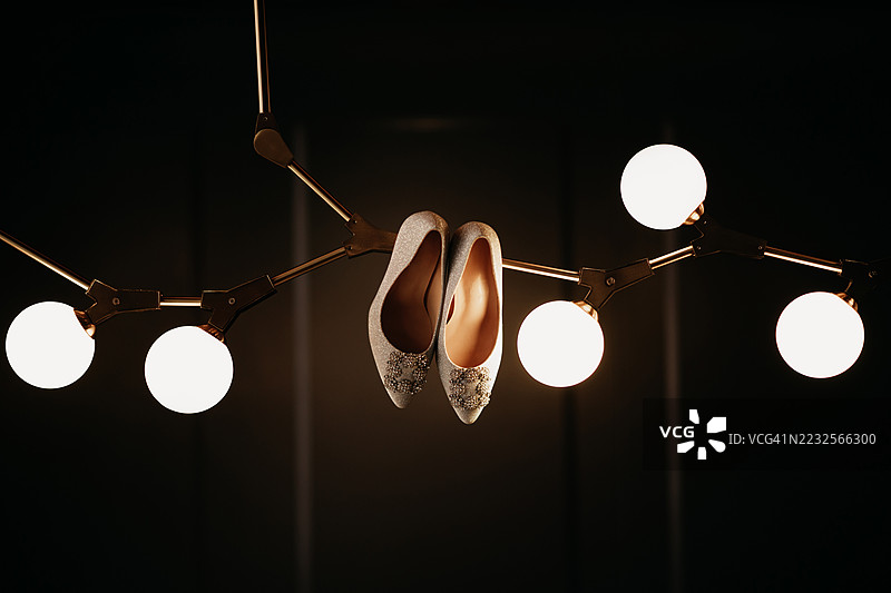优雅的高跟鞋悬挂在现代吊灯上图片素材