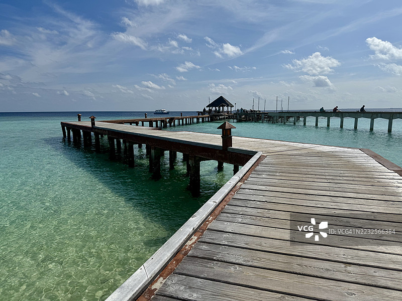 木栈道延伸至碧蓝的海洋，映衬着蓝天图片素材
