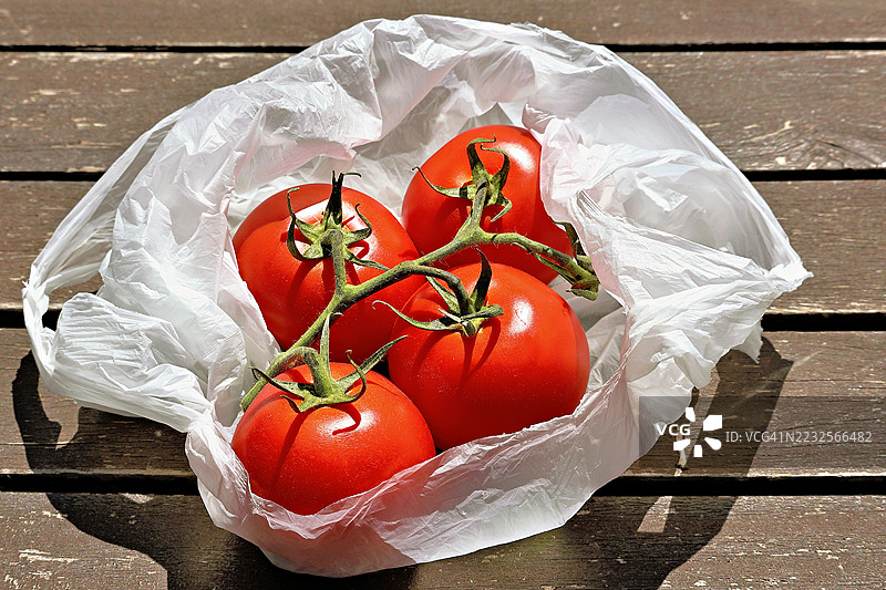 新鲜番茄装在塑料袋里放在木桌上图片素材