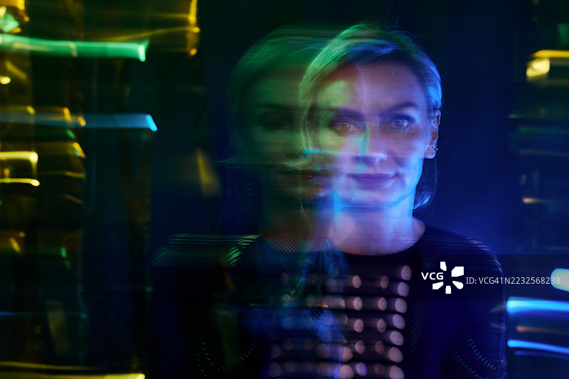 多重曝光的金发女性在霓虹灯下。长时间曝光的彩色光效。图片素材