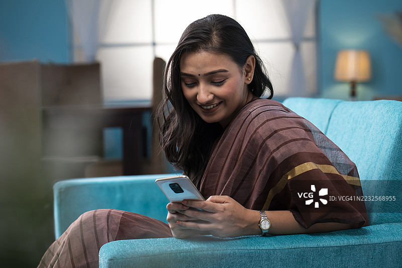 年轻女性坐在沙发上使用手机图片素材