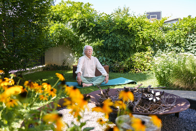 一位西班牙裔绅士在绿意盎然的后院练习正念图片素材