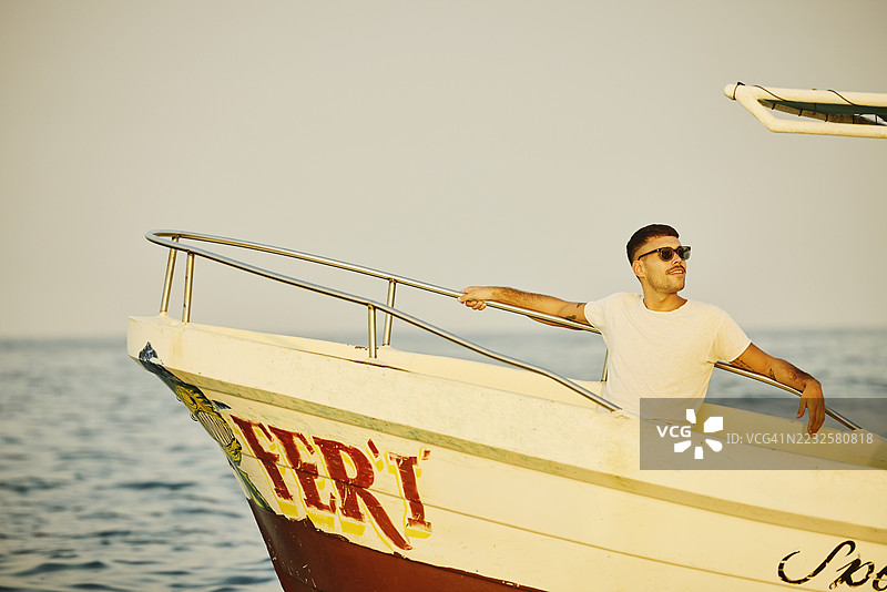 中景男性游客在度假时放松地坐在渔船上图片素材