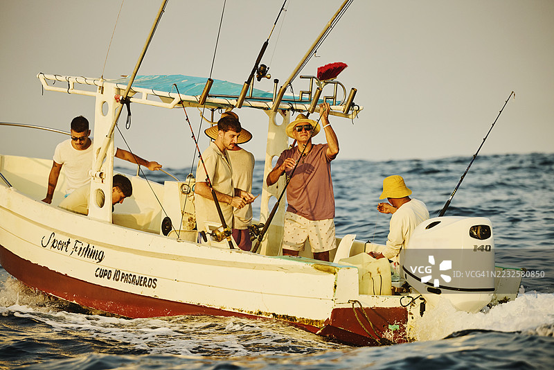 朋友们在船上准备钓鱼竿，进行深海旅行的广角镜头图片素材
