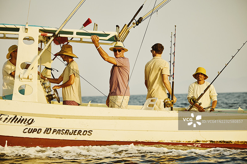 宽镜头拍摄的老父亲和成年儿子们在深海钓鱼之旅中图片素材