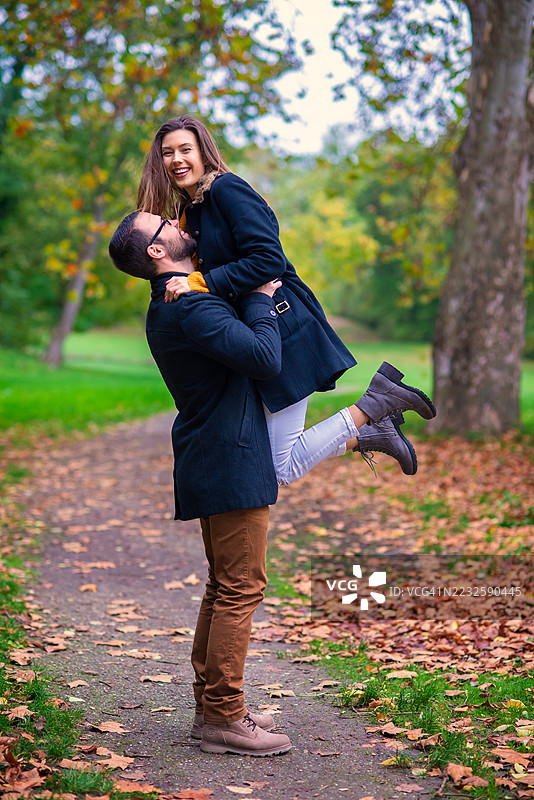 年轻快乐的情侣在秋天的公园里玩耍图片素材