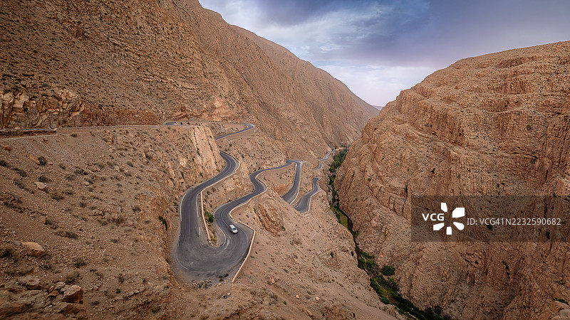 日落时分,蜿蜒的山路上有一辆车,沿着一系列发夹弯驶向著名的达德斯河峡谷,这里是阿特拉斯山脉的自然地标,位于摩洛哥的布马尔内·达德斯 - 蒂内里赫省 - 德拉-塔菲拉勒。图片素材