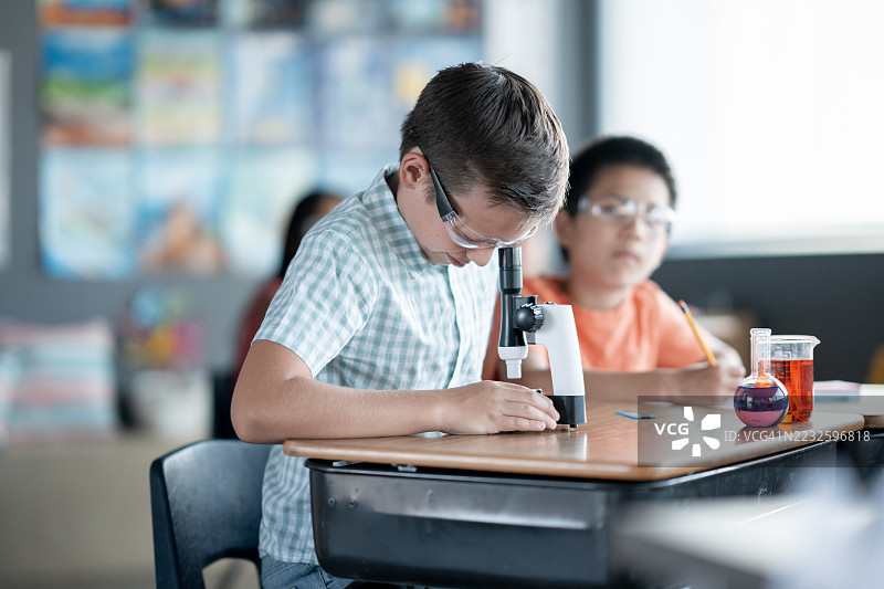 学生在教室里使用显微镜和实验设备进行科学实验图片素材
