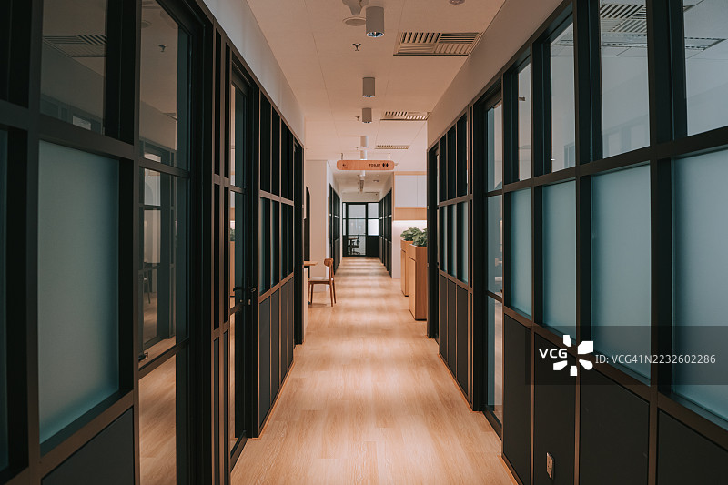 现代办公室走廊内部，配有玻璃隔断和木地板。图片素材