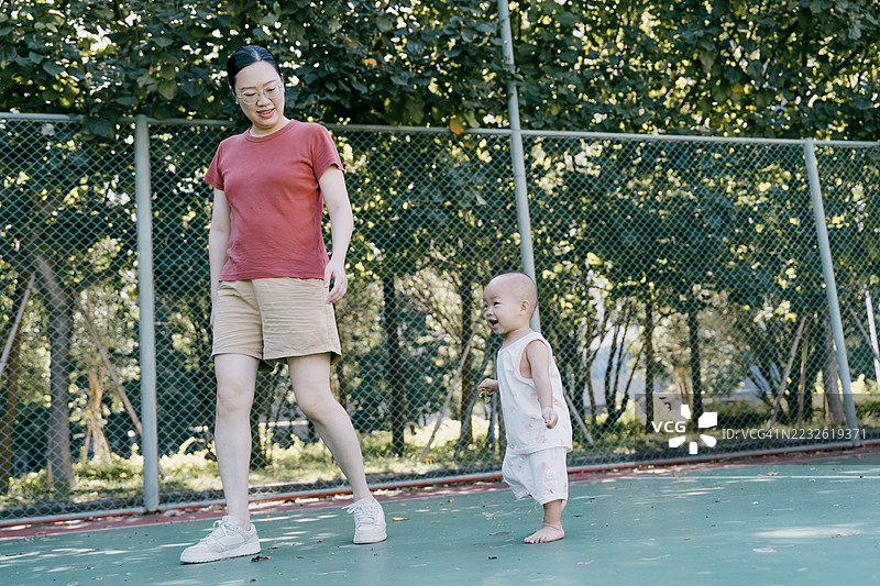 亚洲母亲在篮球场上与女婴玩耍图片素材