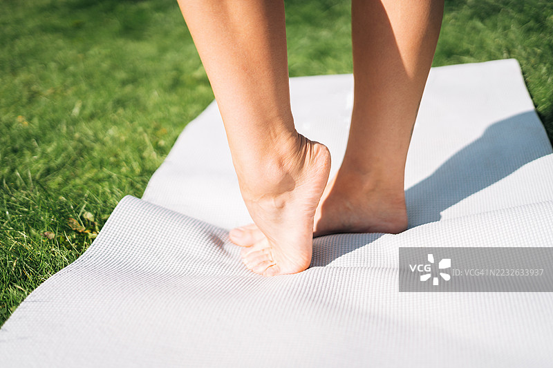 女性的脚放在瑜伽垫上，特写脚趾和足弓，适合锻炼或放松时使用。图片素材