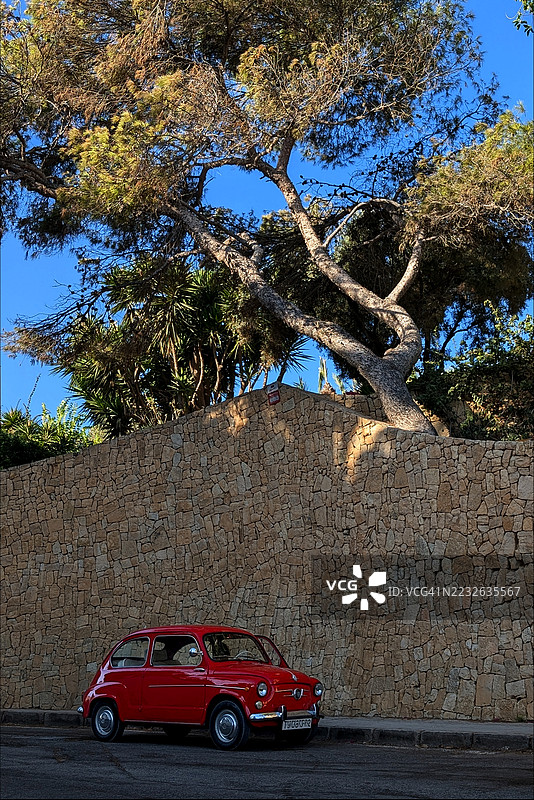 阿利坎特石墙旁停放的复古红色汽车图片素材