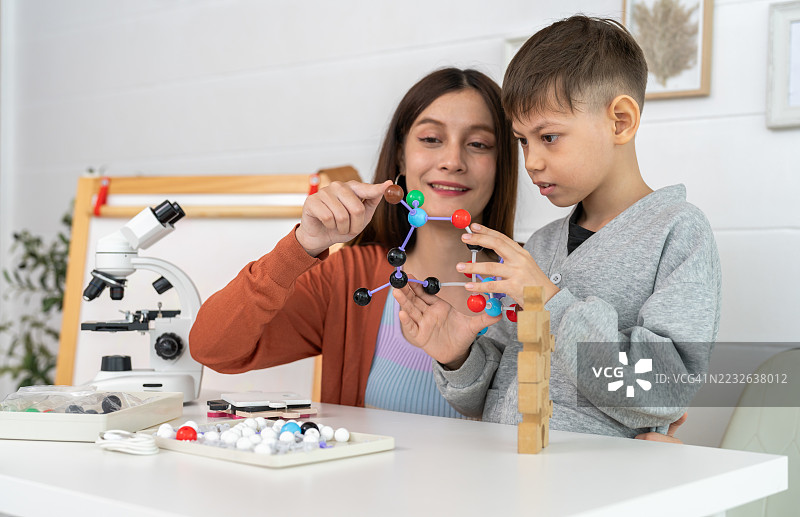 年轻男孩在家与老师一起学习科学，使用彩色原子搭建分子模型，快乐的家庭学校化学知识发展，STEM教育，儿童创意活动学习图片素材