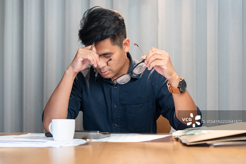 疲惫的男人在加班后拿着眼镜图片素材