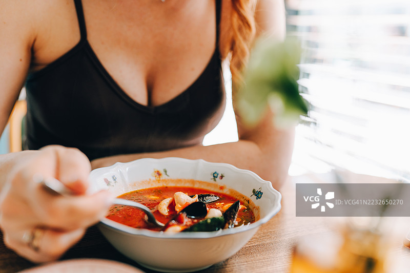 女人的手和海鲜汤。餐厅里美味的清汤。图片素材