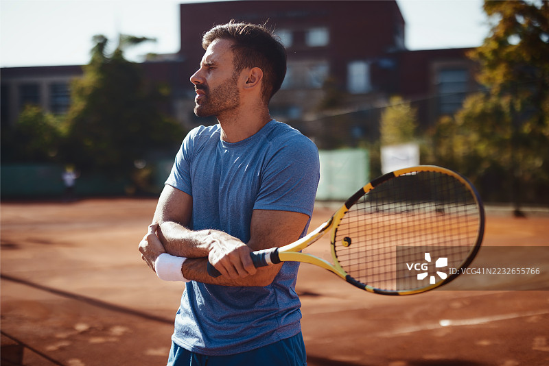 网球运动员在红土场比赛中因肘部疼痛而捂住肘部图片素材