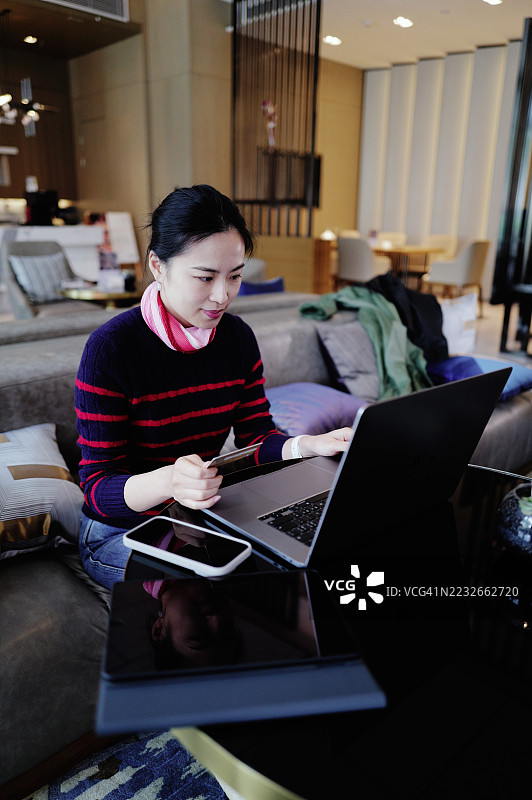 快乐的女性使用信用卡和笔记本电脑进行在线购物图片素材