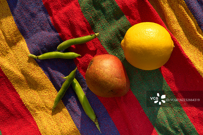 黄色柠檬、红色梨和绿色豆荚在条纹纹理背景上图片素材
