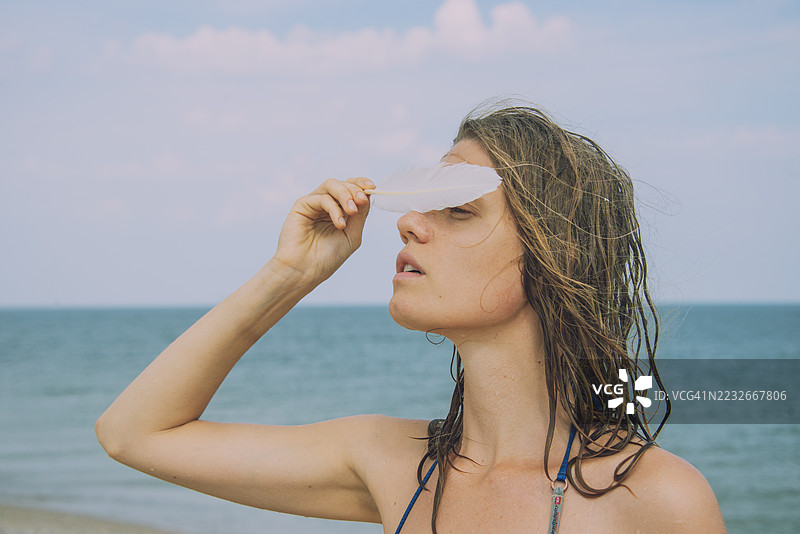 年轻女性的肖像，手持海鸥羽毛图片素材