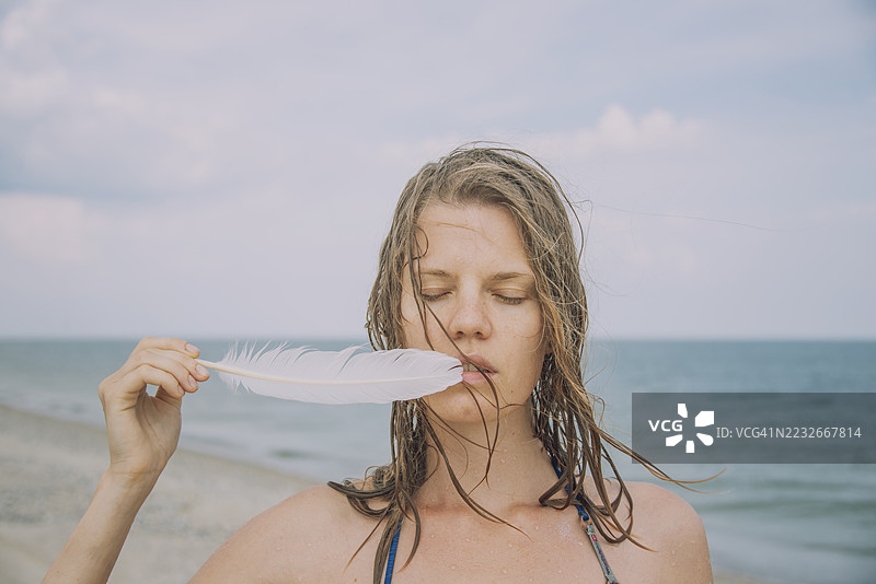 年轻女性的肖像，手持海鸥羽毛图片素材