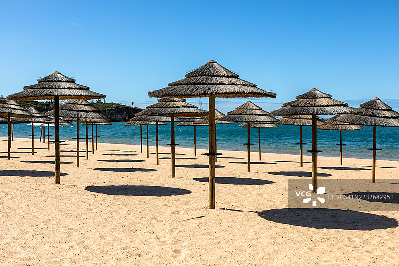 理想的沙滩，配有稻草阳伞和帆船，位于葡萄牙费拉古杜图片素材