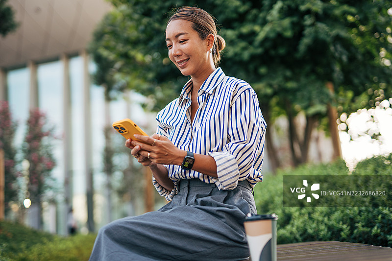 商务女性在户外休息时间使用智能手机图片素材