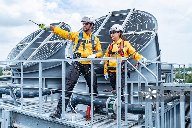 建筑师在屋顶上审查暖通空调系统的蓝图图片素材