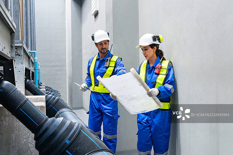 工程师在工业管道附近分析蓝图图片素材