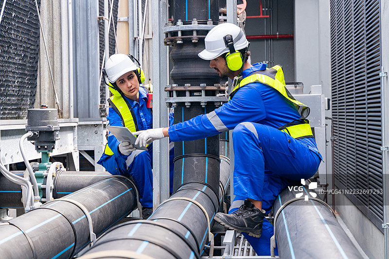 工程师在工业管道附近讨论蓝图图片素材