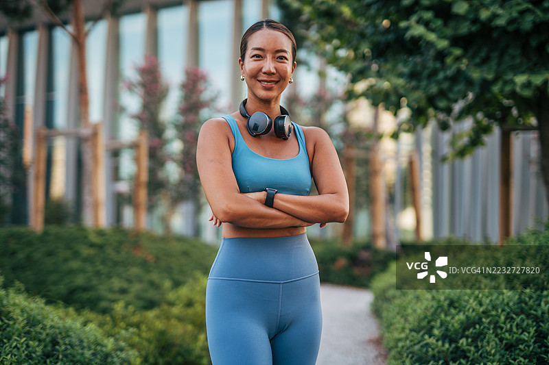 在公园里微笑并交叉双臂的亚洲女运动员图片素材