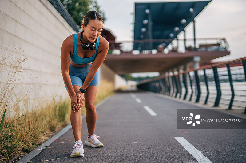 年轻的运动女性在户外慢跑时感到膝盖疼痛图片素材