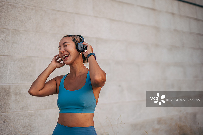 年轻的运动女性戴着耳机听音乐并微笑图片素材