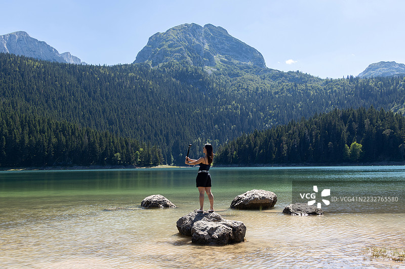 年轻游客在欧洲黑山杜米托尔国家公园扎夫拉克市镇的黑湖畔进行视频博客拍摄图片素材