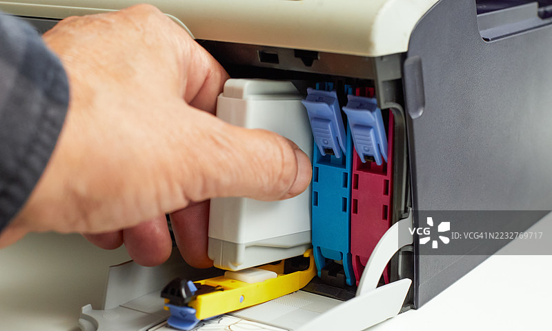 技术人员在电脑打印机中更换墨盒的特写镜头图片素材