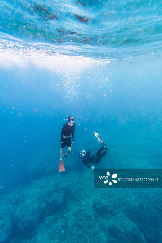 父亲和女儿在清澈的蓝色水域潜水图片素材