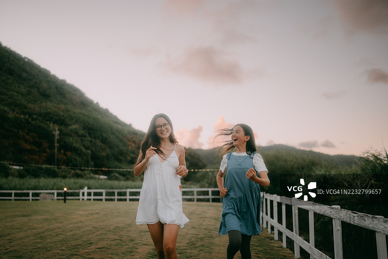 两个姐妹在海边的后院里奔跑，夕阳西下，日本图片素材
