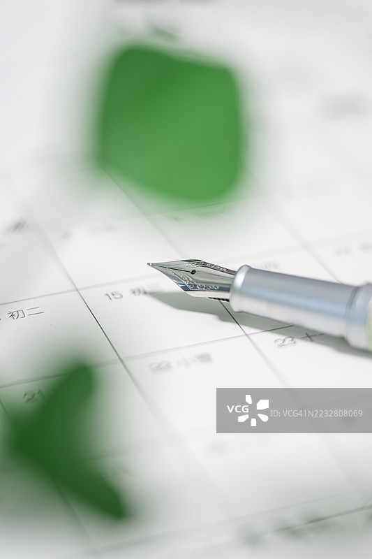 钢笔在桌面日历上。图片素材