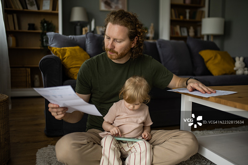 父亲在家里与他的小女儿一起阅读财务账单。图片素材